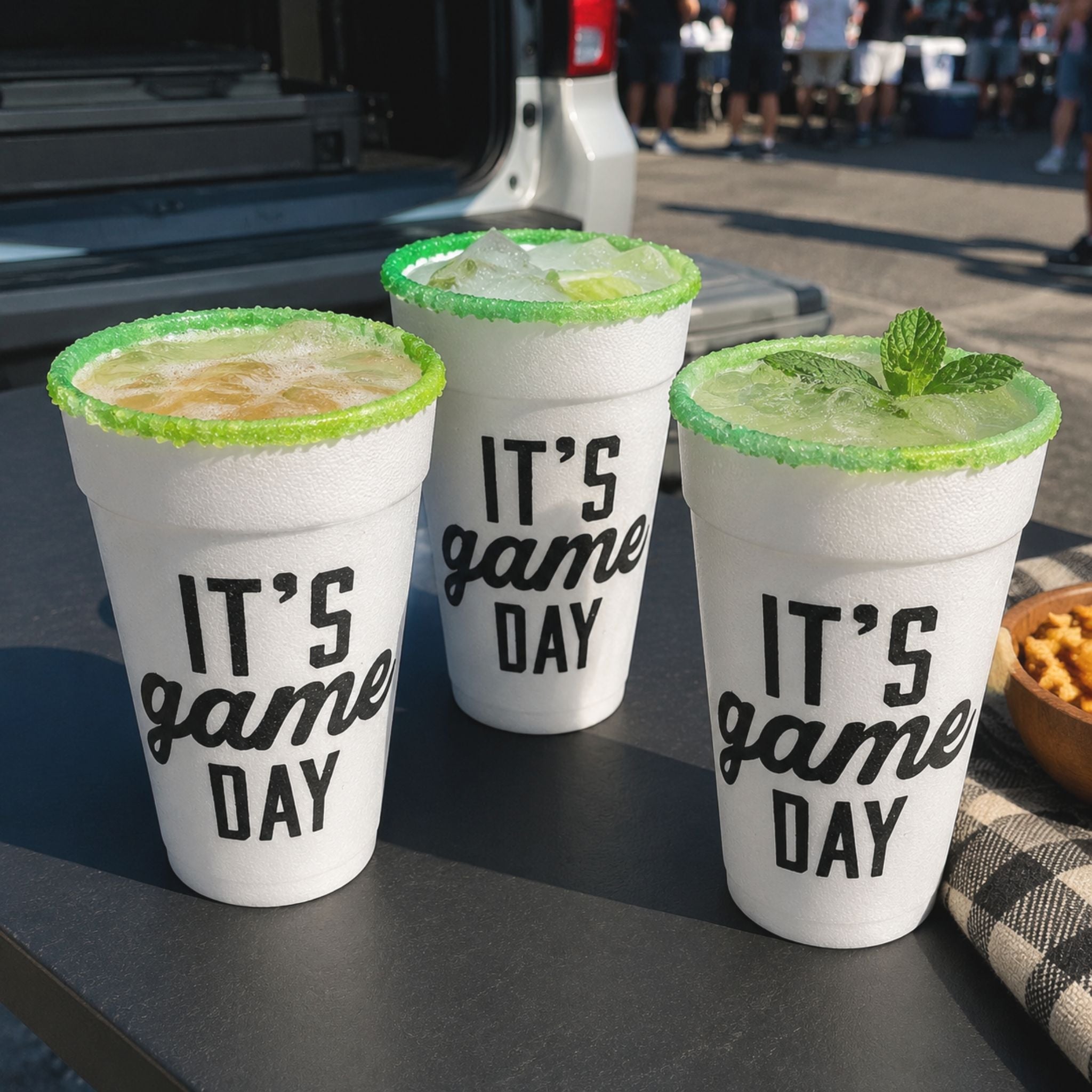 Three Rita Rims Game Day Salt & Lime cups filled with a beerita, ranch water, and sparkling lime mocktail at a tailgate.