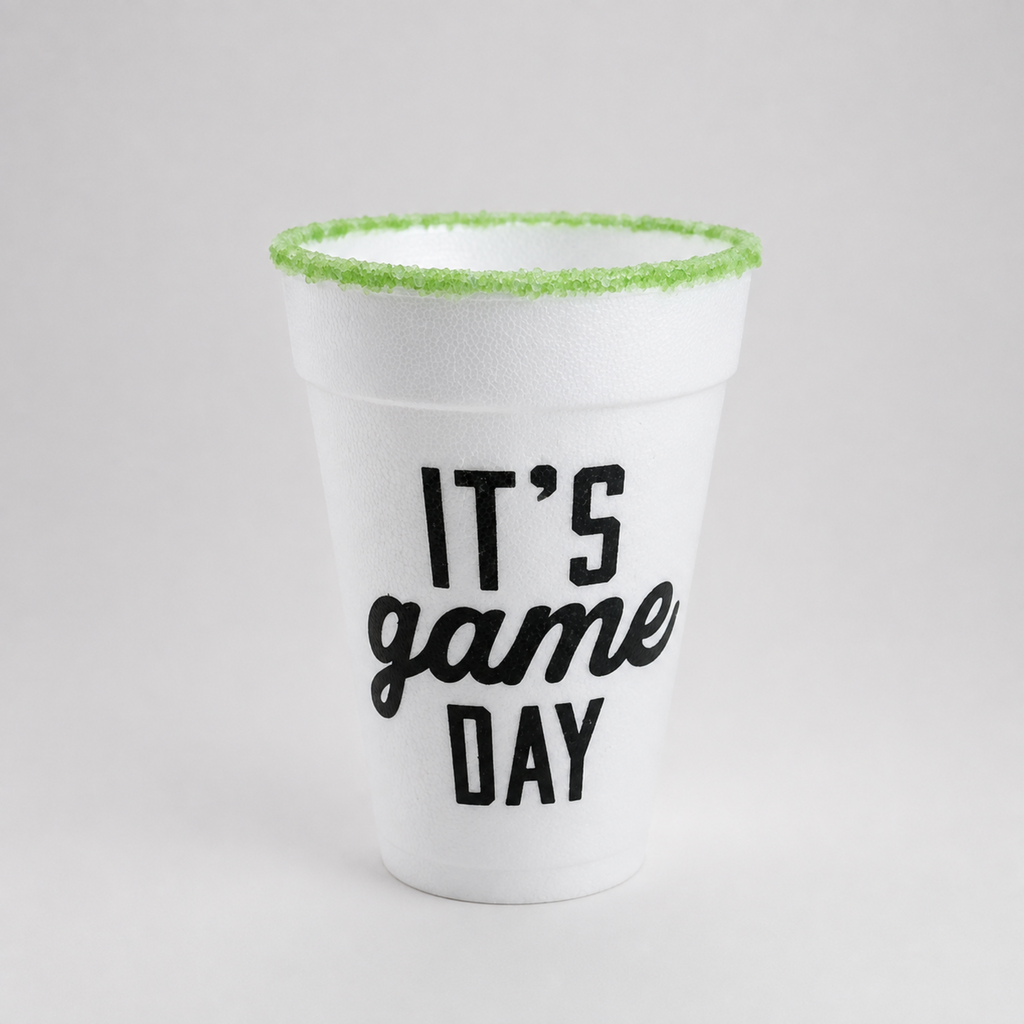 A white foam cup with 'IT'S game DAY' printed in black on the front, featuring a bright green sugar-rimmed edge, set against a neutral light gray background.