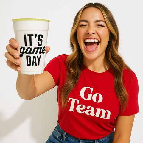 Person wearing a red 'Go Team' shirt and holding a 'It's Game Day' cup.