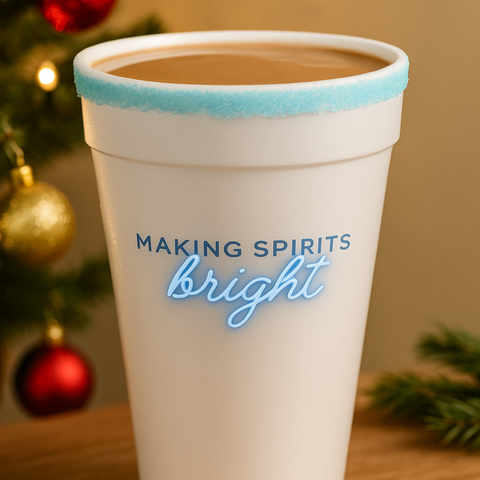 A tall 16 oz white styrofoam cup with a blue peppermint sugar rim and the ‘Making Spirits Bright’ holiday graphic, filled with a warm winter beverage. Festive Christmas décor in the background, styled for product photography and seasonal drinkware marketing.