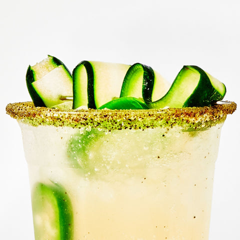 Cocktail with cucumber slices and a salted rim on a white background