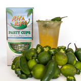 Box of 'Rita Rims' party cups with jalapeños, a glass of yellow liquid, and jalapeños on a white background.