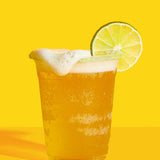 Glass of beer with a lime wedge on a yellow background