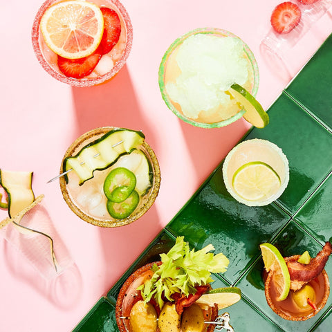 Assorted small appetizers on a green tray with a pink background
