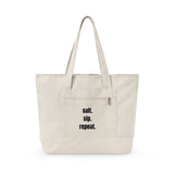 An off-white canvas tote bag with black text reading 'salt. sip. repeat.'