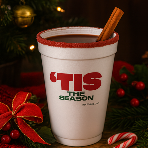 Cranberry-rimmed ‘TIS THE SEASON’ holiday cup filled with a warm drink, styled with ornaments, candy canes, and Christmas décor for festive hosting.